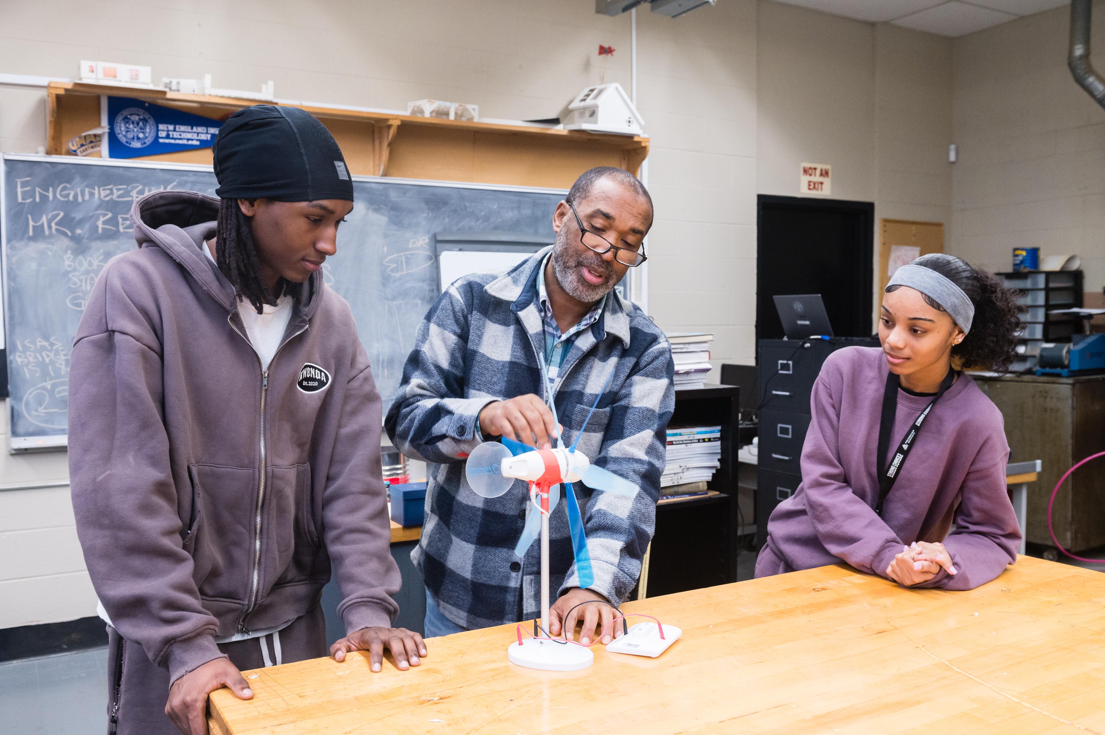 Students work with an educator on a wind turbine model