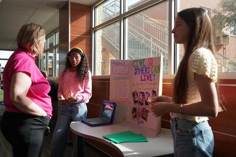 IB Students present their Give So Others Can Live project to a staff member
