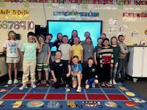 A group of children wearing colorful glasses posing together in a classroom.