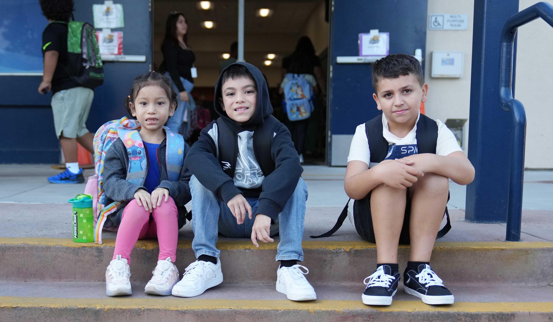 three students sitting on steps outside of cafeteria