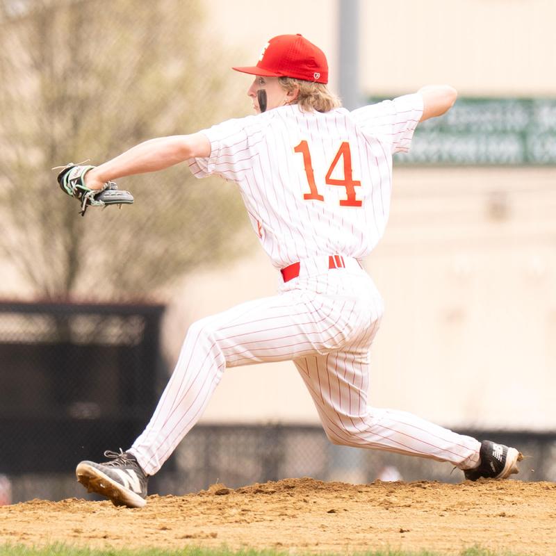 A baseball player in a red cap and striped uniform pitching on the mound.