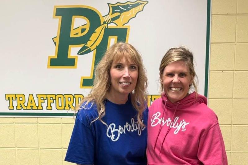 Project organizer, Mrs. Jenny Winter, and Megs Yunns stand in front of a PT sign