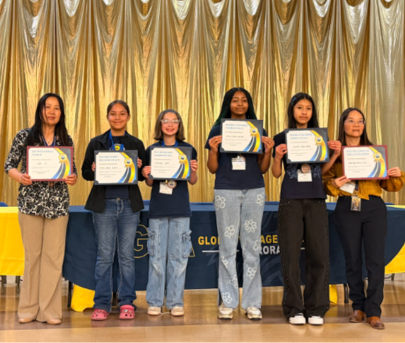Two teachers and four students holding certificates and standing in front of a gold curtain