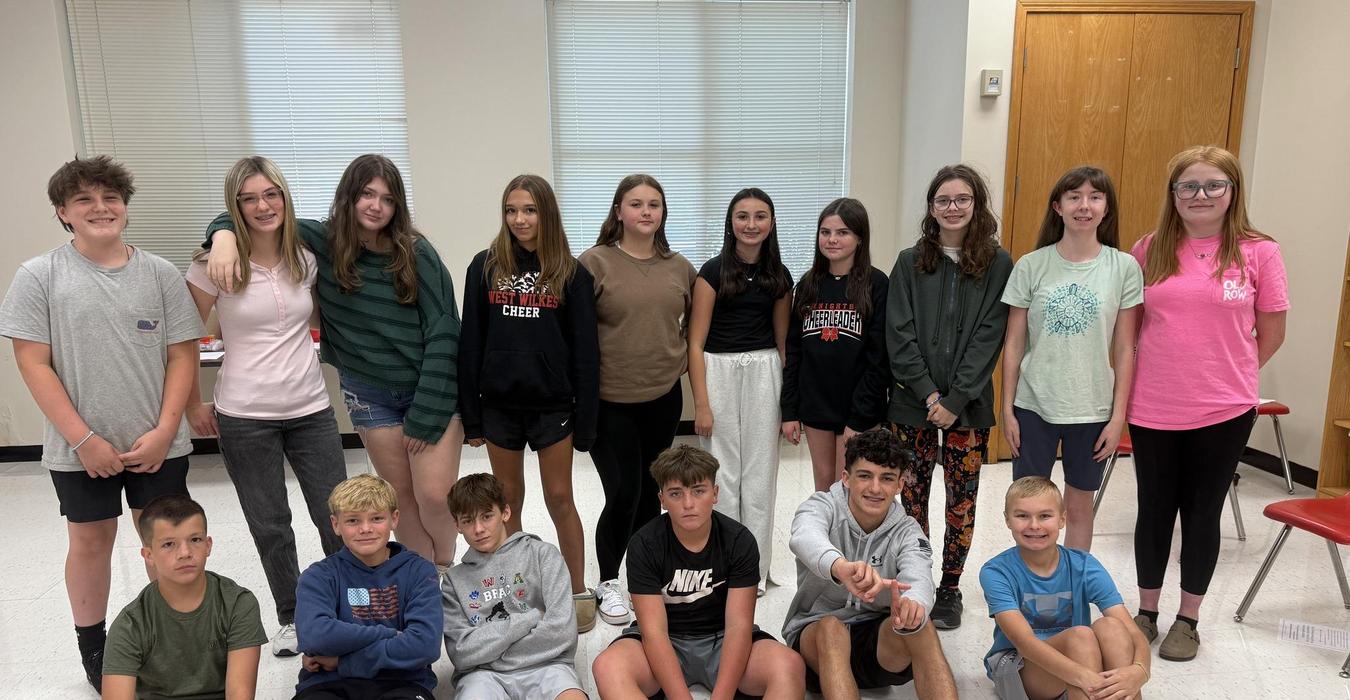 A large group of diverse students posing together in a classroom.