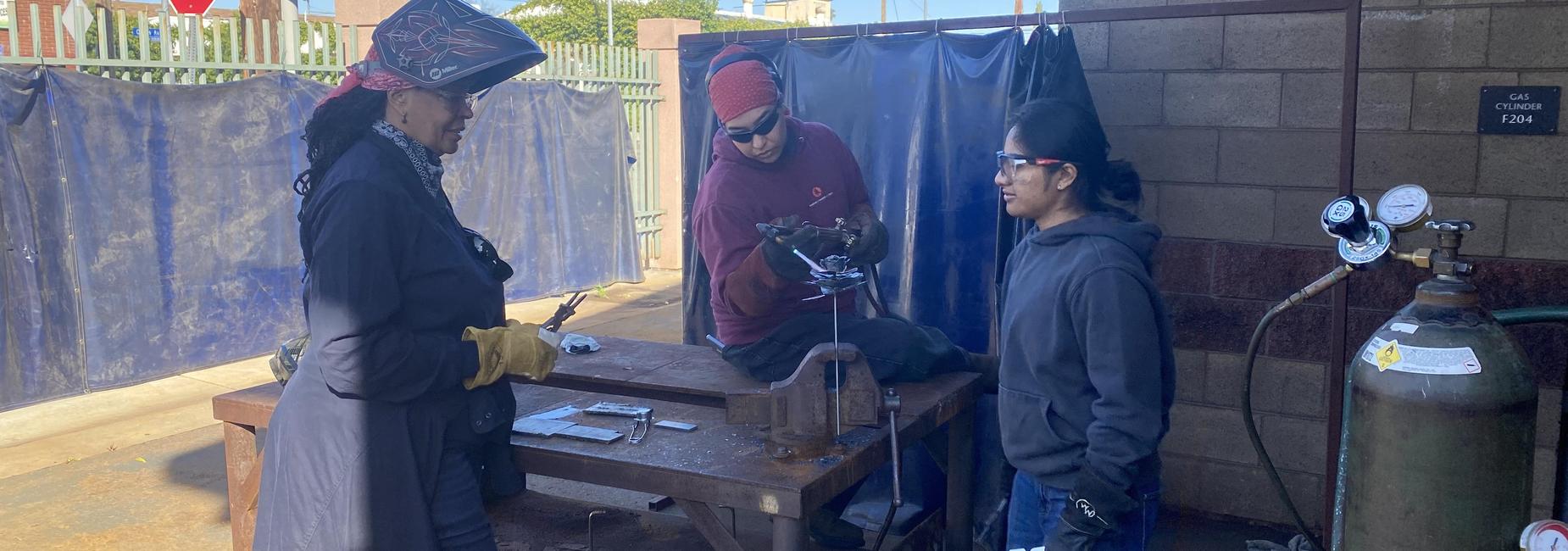 Welding students working together to make a metal flower