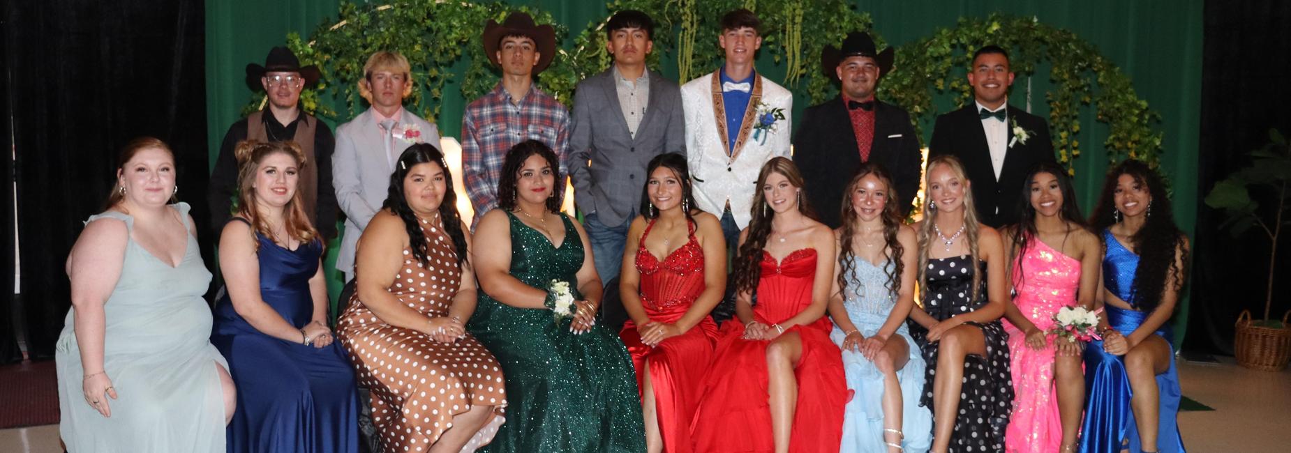 Group of young adults in formal attire, seated together in a festive setting.