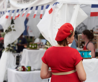 Woman in red standing in front of row of white booths with French flags