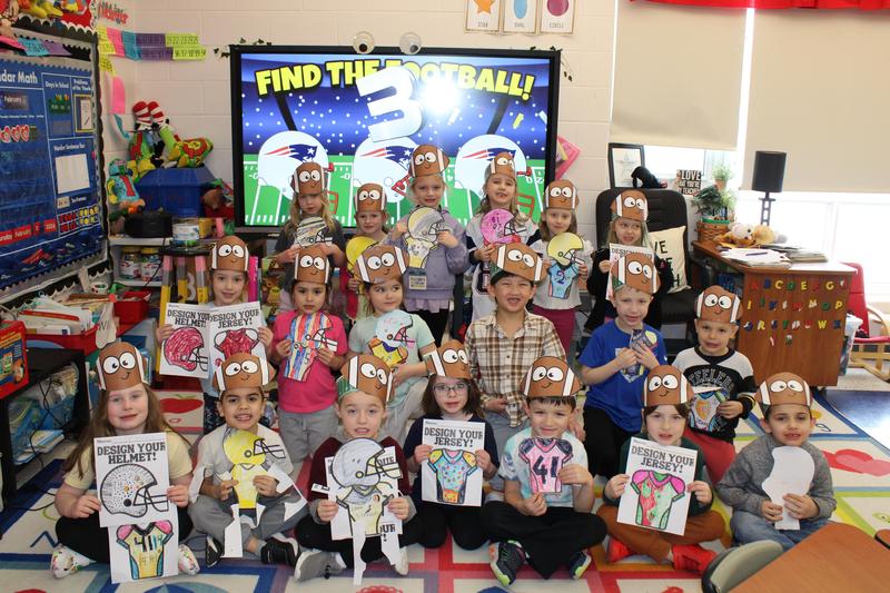 class of kindergarteners with football crowns holding colored jerseys and helmets