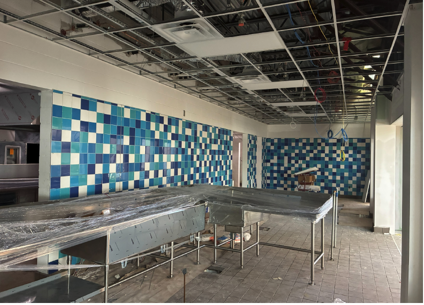 Construction site with blue and green tiled walls and metal counters.