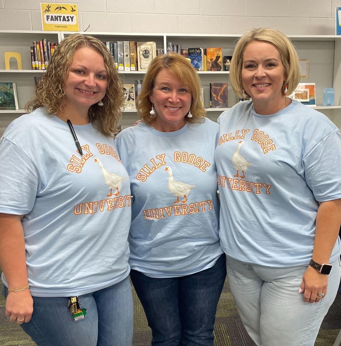 3 Women posing for a picture all wearing the same shirt.