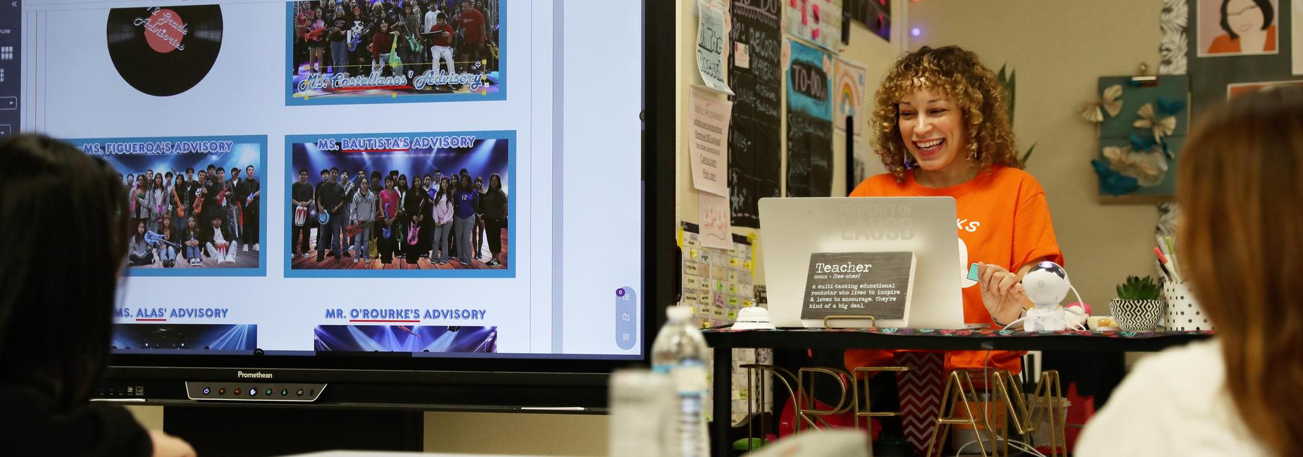 Teacher energetically teaching in front of a presentation and smiling.