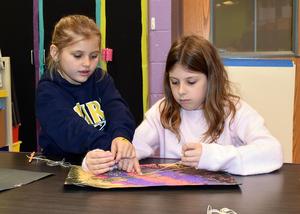 two girls tying a piece of string
