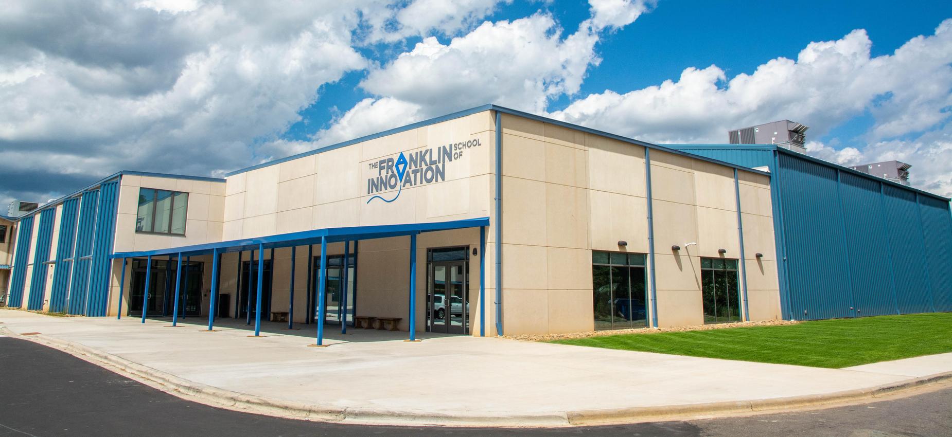 Photo of the front of a school building with clouds in the background