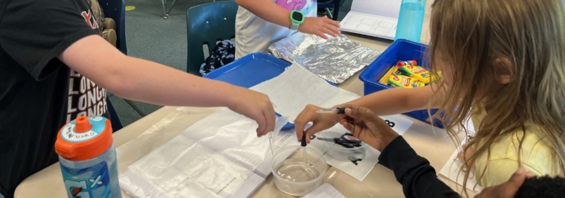 Students engaged in various activities at classroom tables.