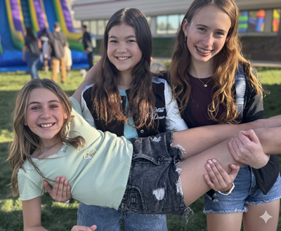 two students holding up a third