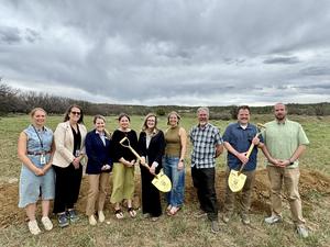 Group of people stand in field before groundbreaking