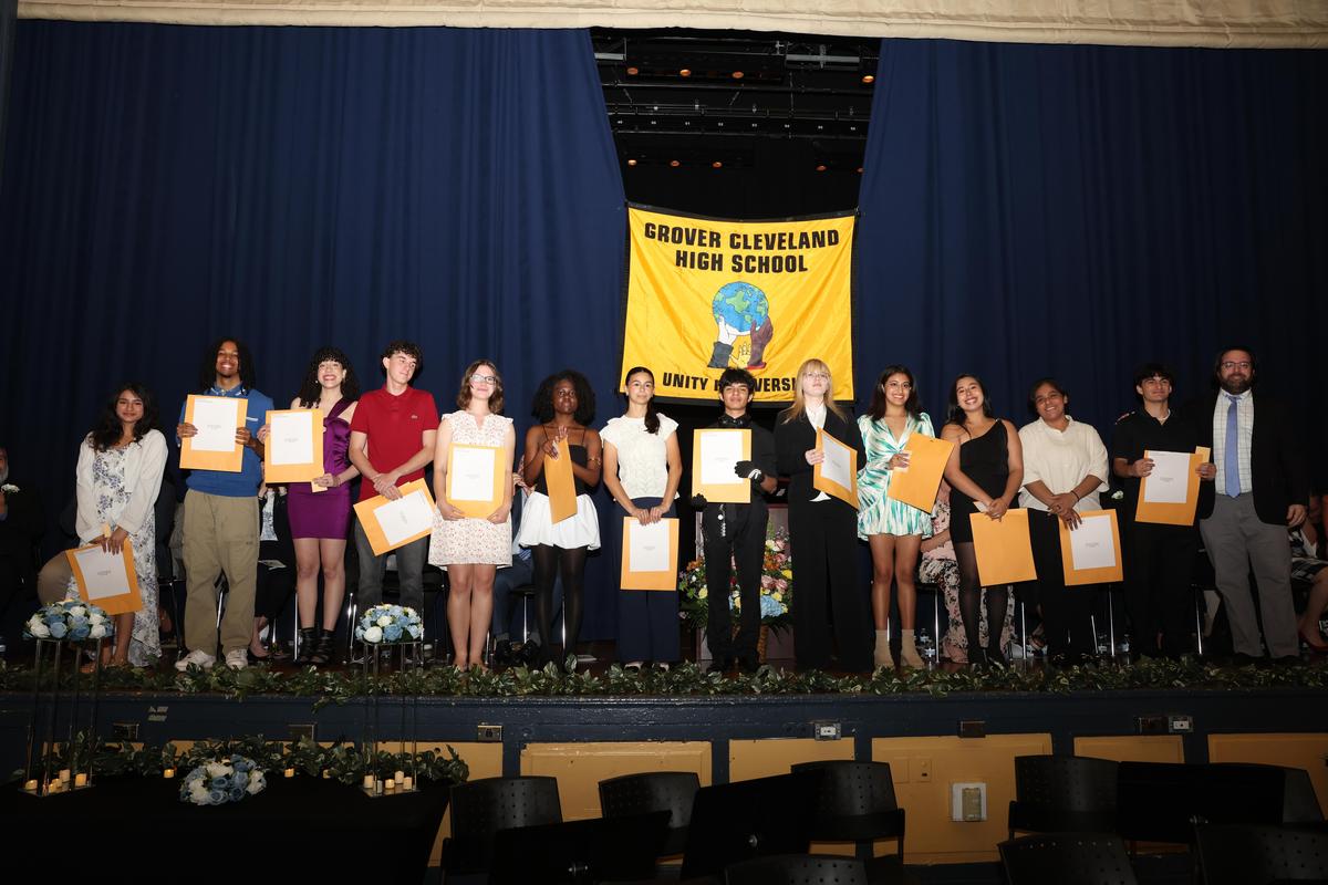 Students on stage holding certificates at a graduation ceremony.