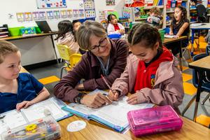 An Arco Iris student and volunteer work together in a workbook in their Beaverton classroom.