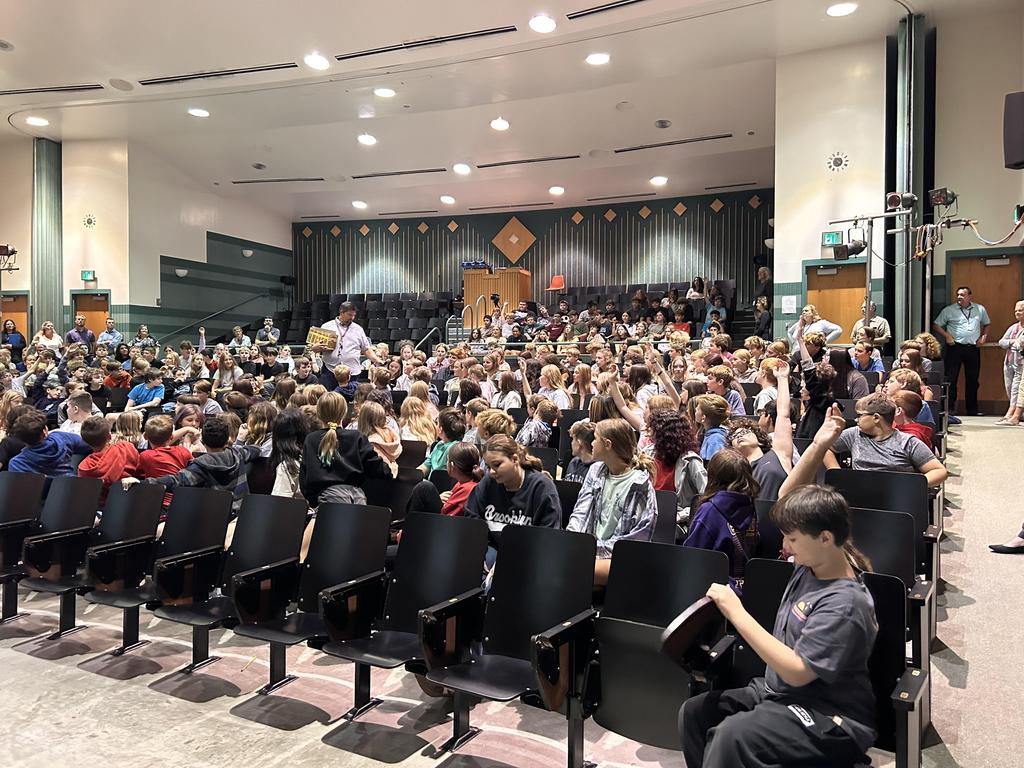 Students in the auditorium, some who have their hand raised.