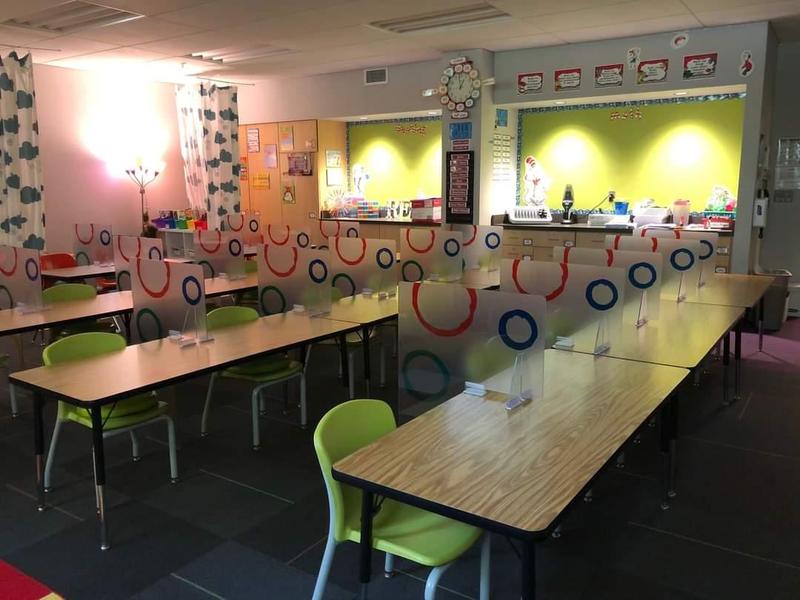 Empty classroom with dividers between desks is shown
