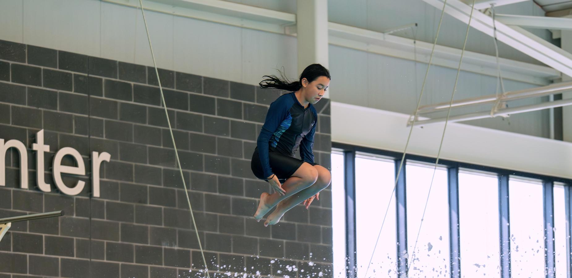 A girl diving into a swimming pool with splashes around her.