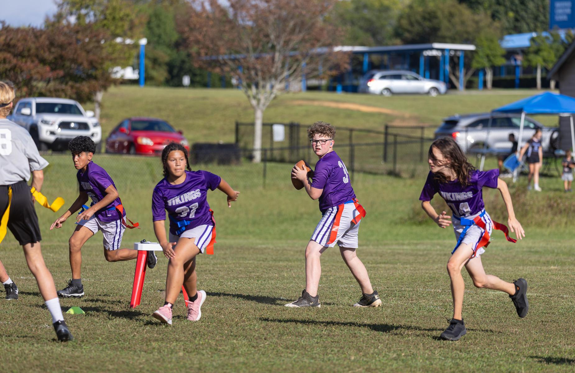 Children playing flag football on a grassy field.