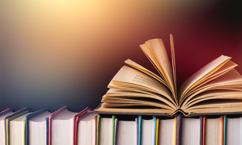 photo of an open book setting on top of stacked books