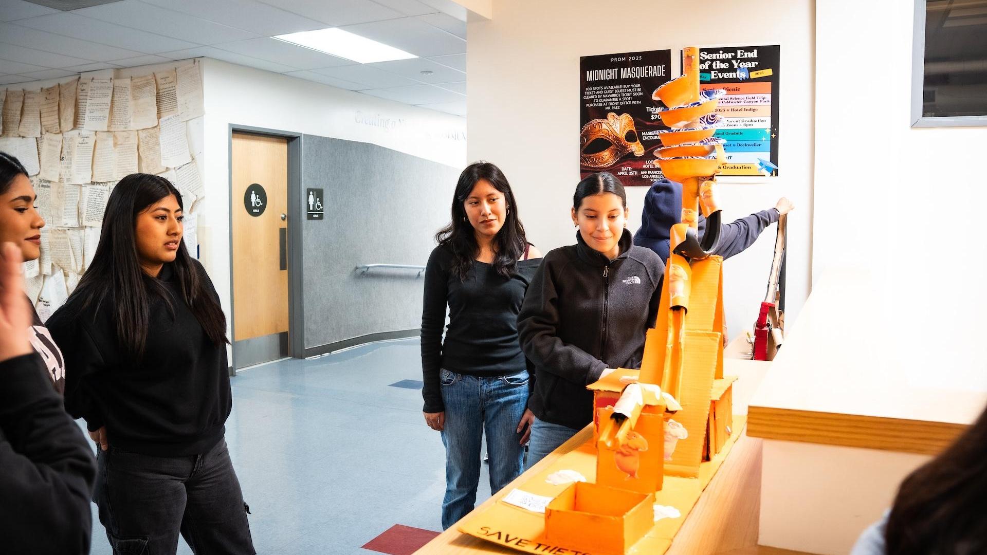 Students observing a project display in a school hallway.