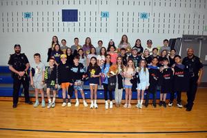 Group of students and police officers posing together in a school gym.