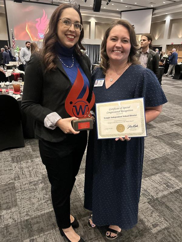 Jessica Cuellar (left) and Brianna Hubnik (right) pose with the district's Phoenix Award