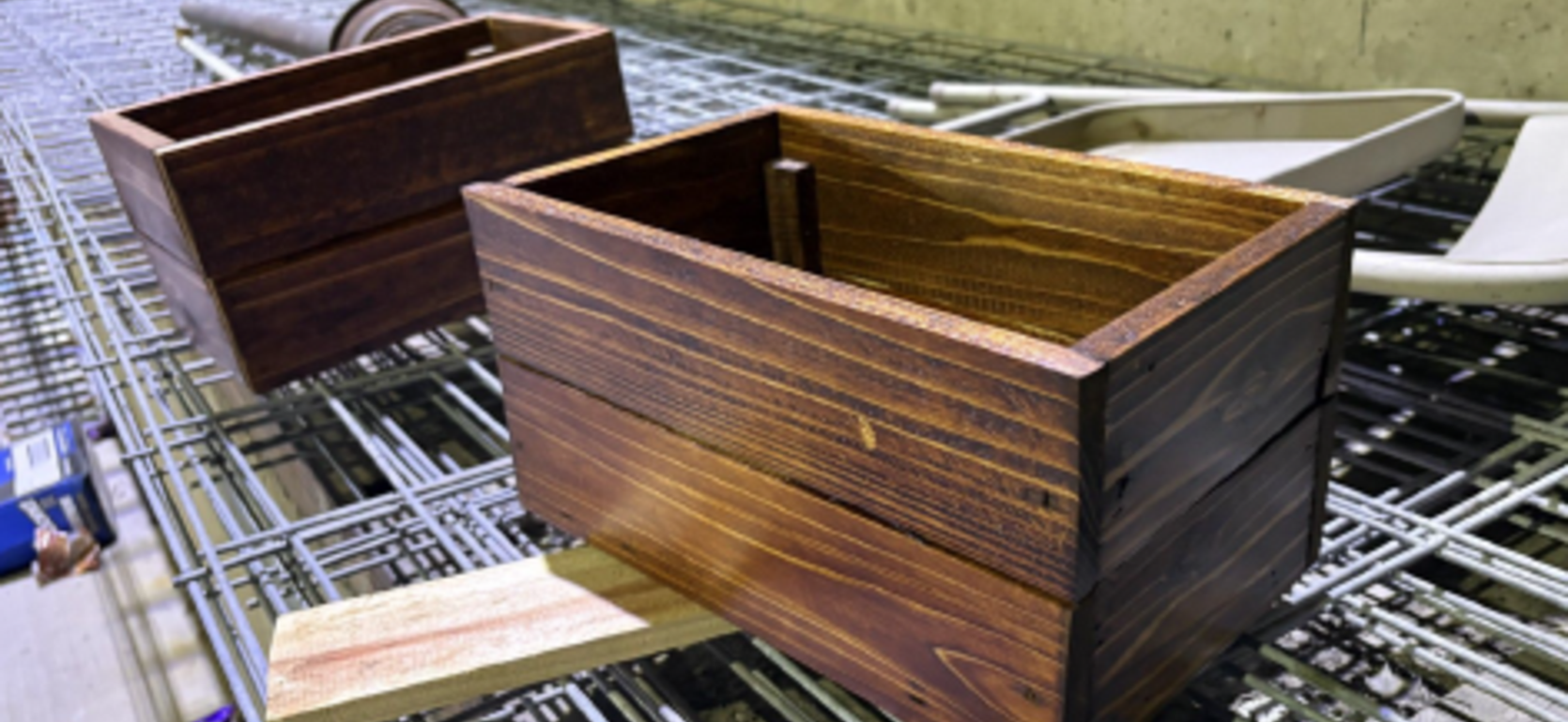Two wooden boxes with a dark finish on a wire rack.