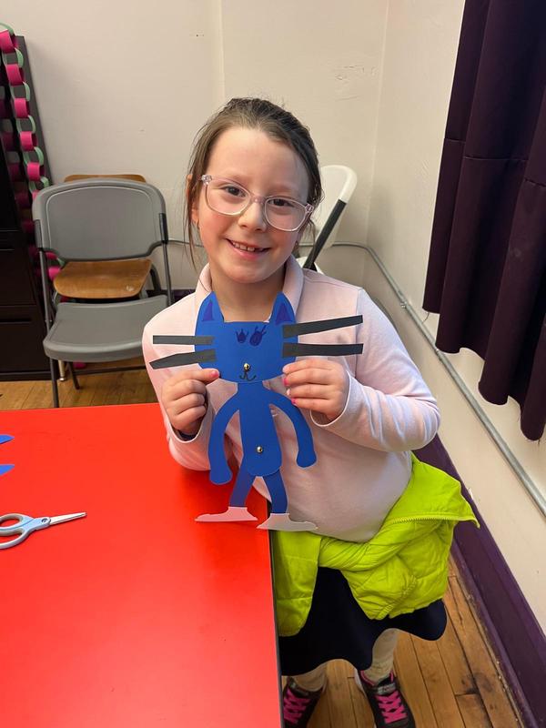 A student shows off her Pete the Cat paper puppet.