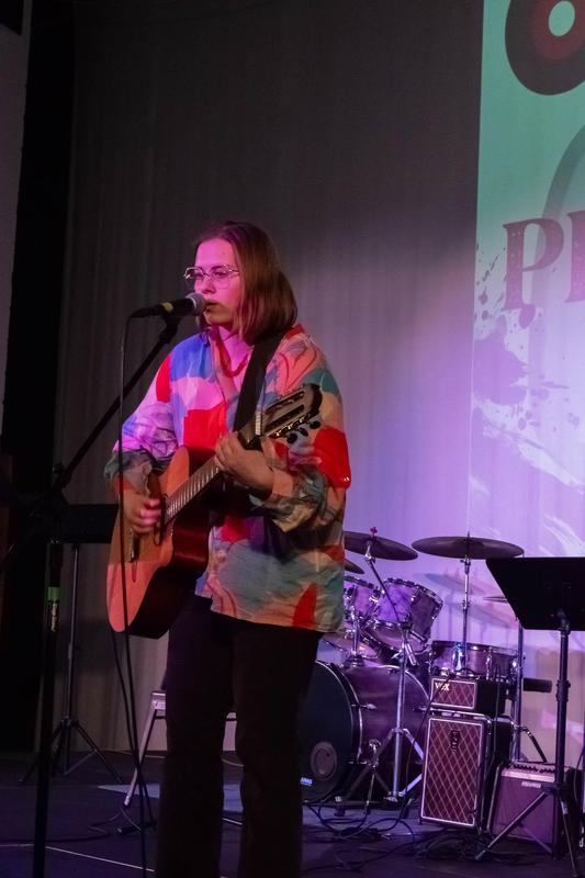 Student singing while playing guitar.