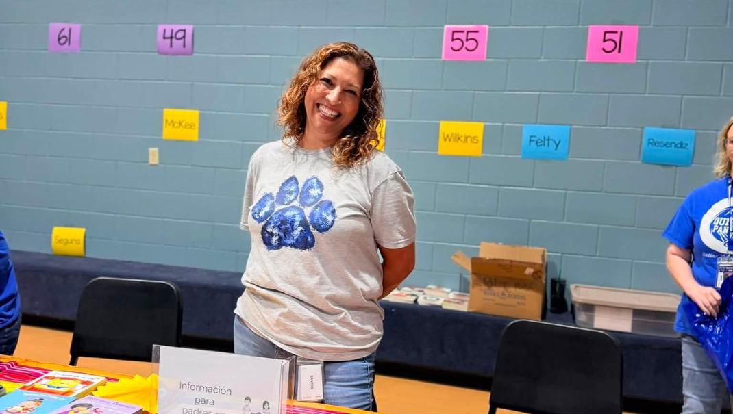 A woman smiling at a table with educational materials.