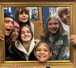 Five teen girl faces inside an open frame as they are smiling