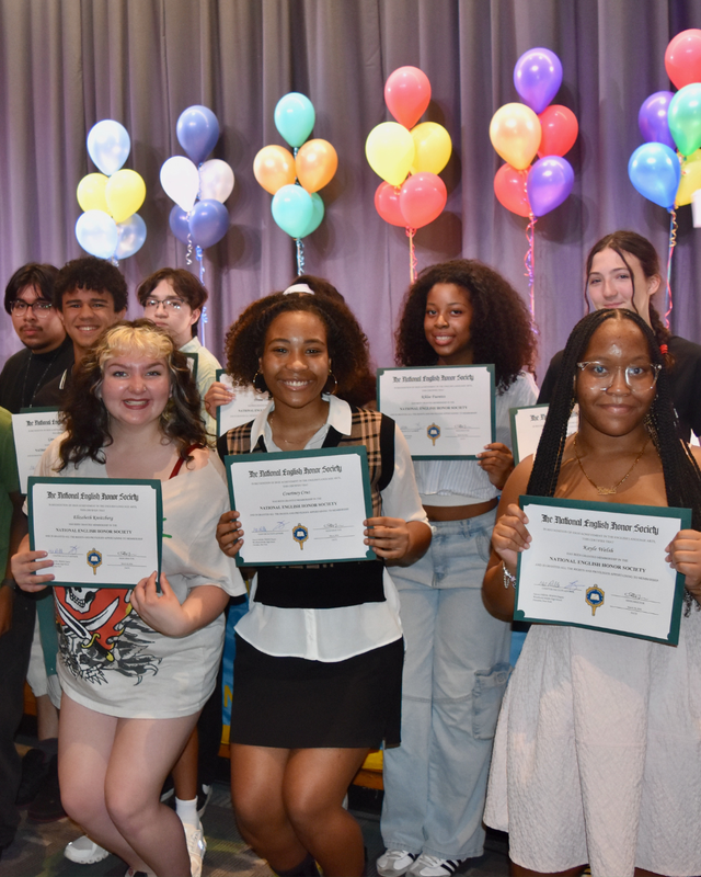 Students hold award certificates at ceremony