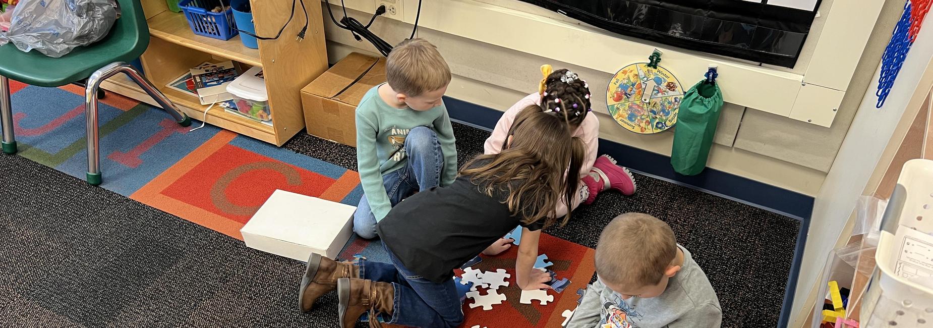 Four students on class carpet working on a floor puzzle