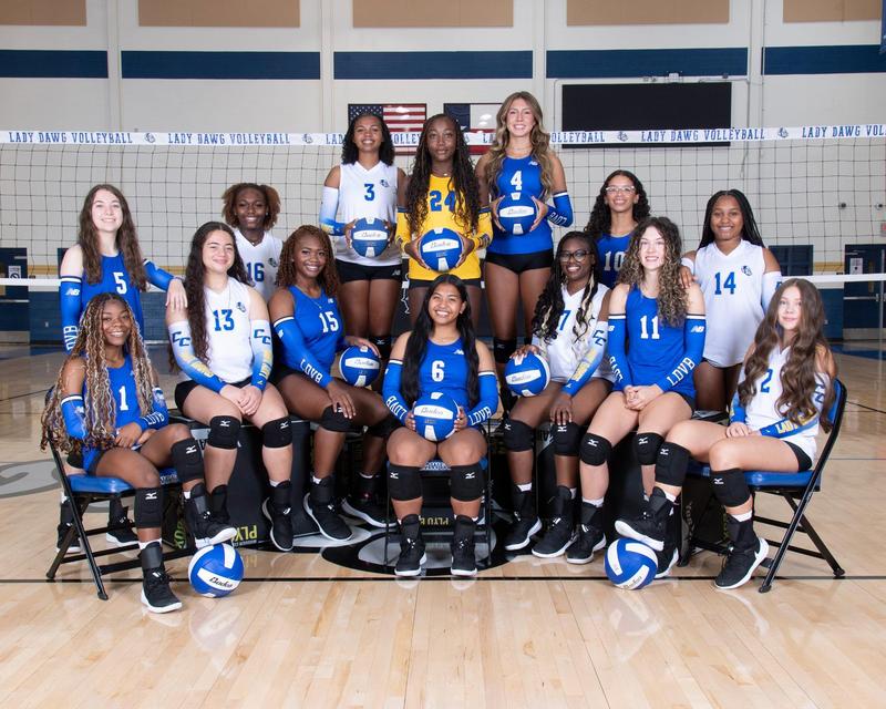 A volleyball team smiling in front of a net