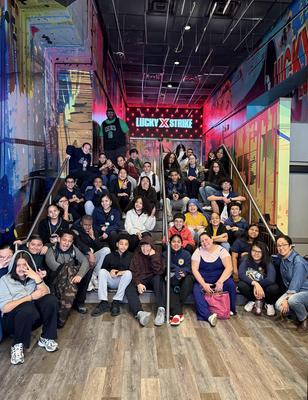 A large group of people posing on stairs inside a colorful venue.