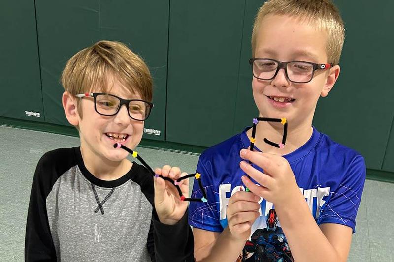 Third-graders Cyrus Vincent and Ben Gable show their finished crafts
