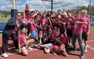 Group of students posing together on a track field, wearing matching red shirts.