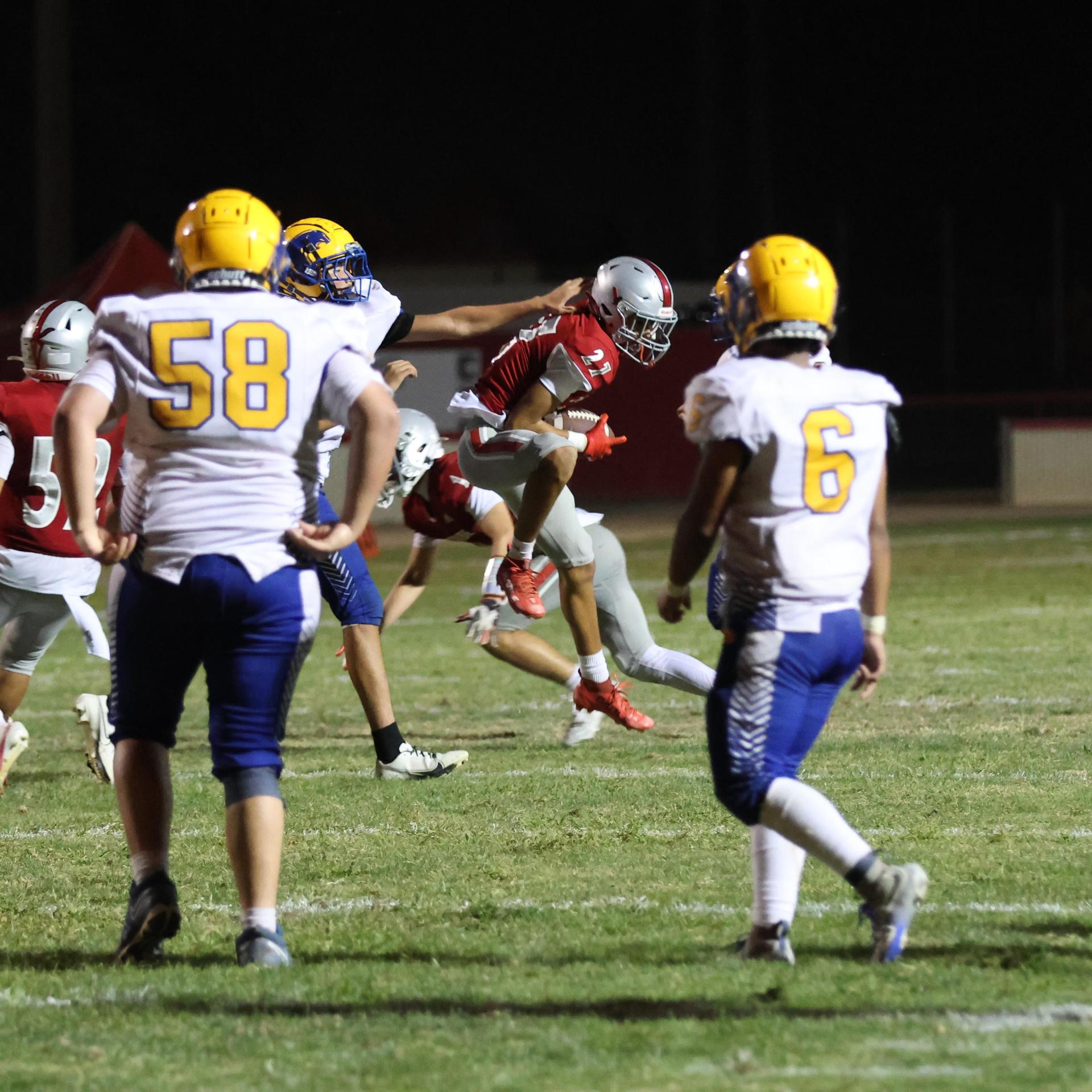 Varsity football players in action against Parlier 83