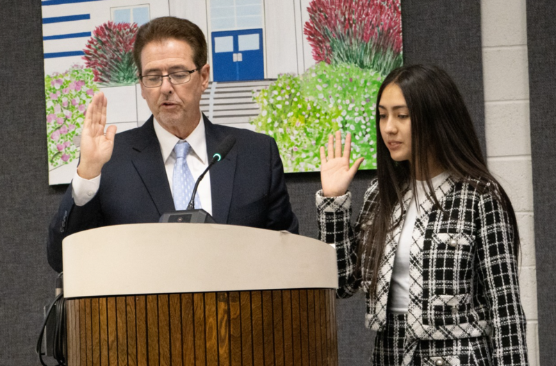 A board member and student stand at a podium