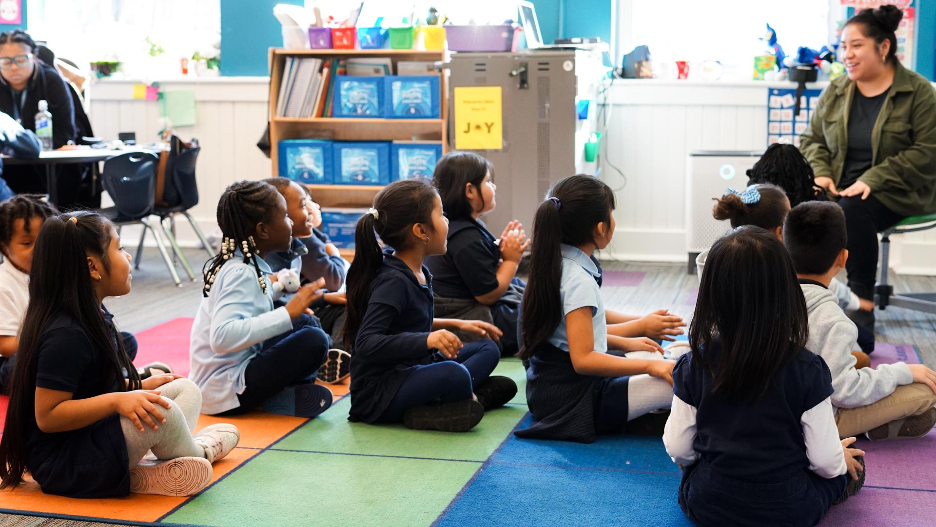 Students sitting on the floor with the teacher 
