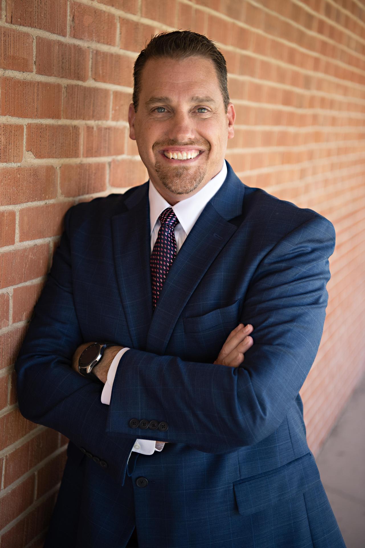 Dale Ponder in a blue jacket and arms crossed against a brick wall