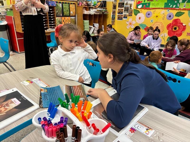 a seventh grade girl read her Gadol picture book to a kindergarten student.