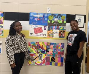 Two girls stand beside their vocabulary word artwork