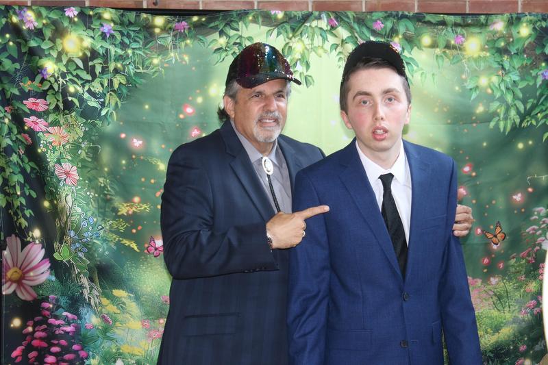 Man and his son; both wearing colorful caps and suits