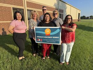 Group of six people holding a sign for America's Healthiest Schools in a grassy area.