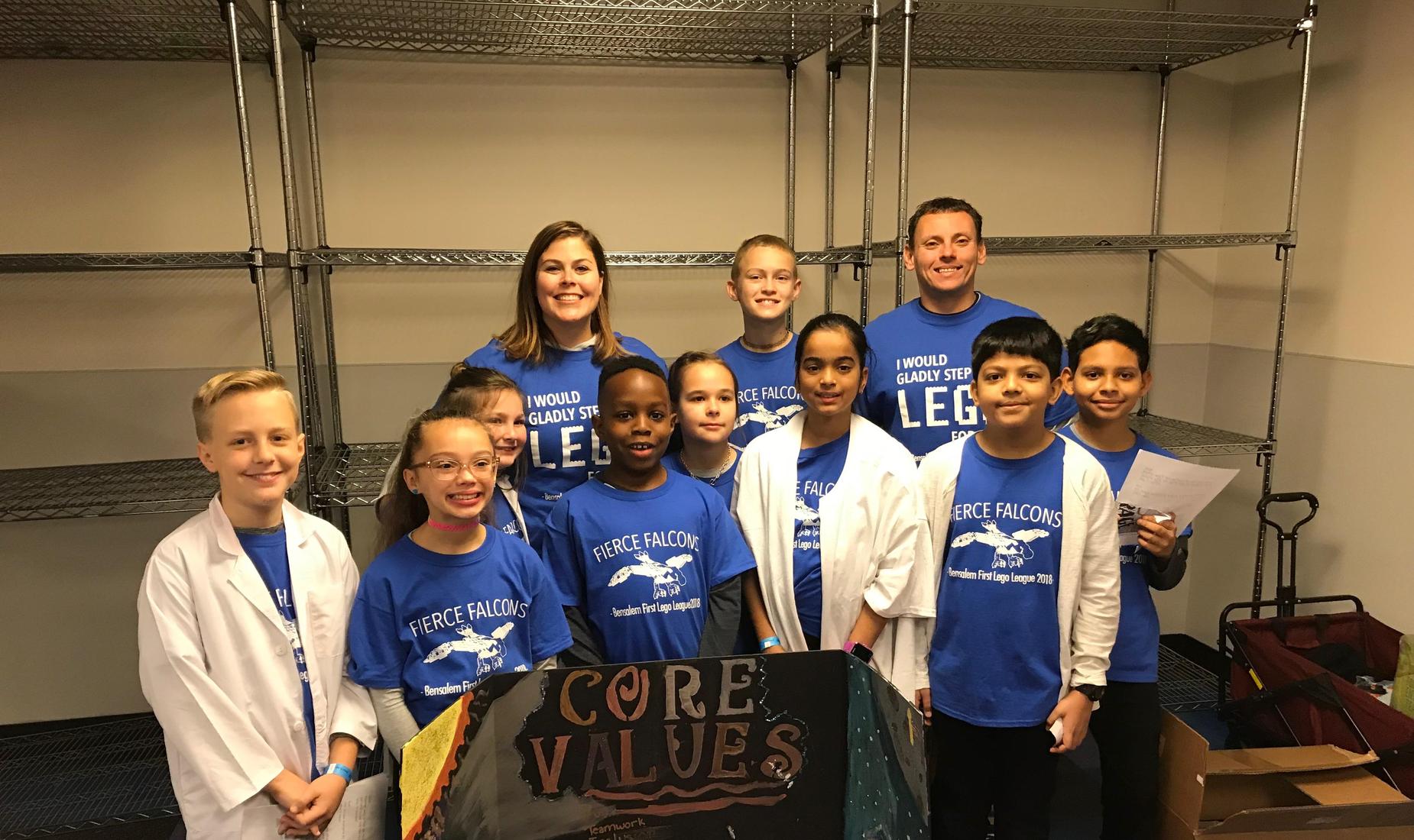 9 boys and girls and their teachers dressed in blue Fierce Falcons shirts ready for their First Lego League Competition